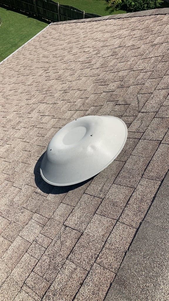 Roof vent cap with hail dents marked in chalk, sitting on an asphalt shingle slope