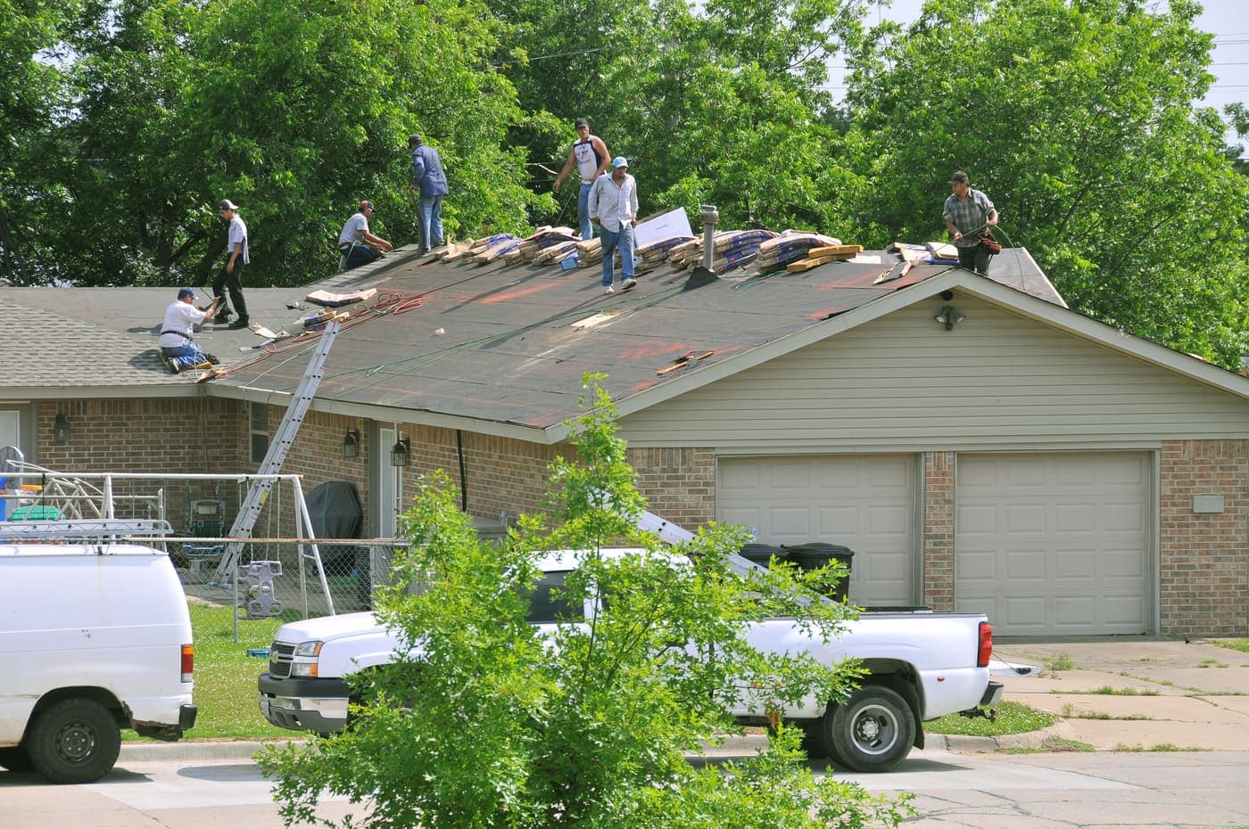 Roofing crew tearing off and replacing an asphalt shingle roof on a single-story home